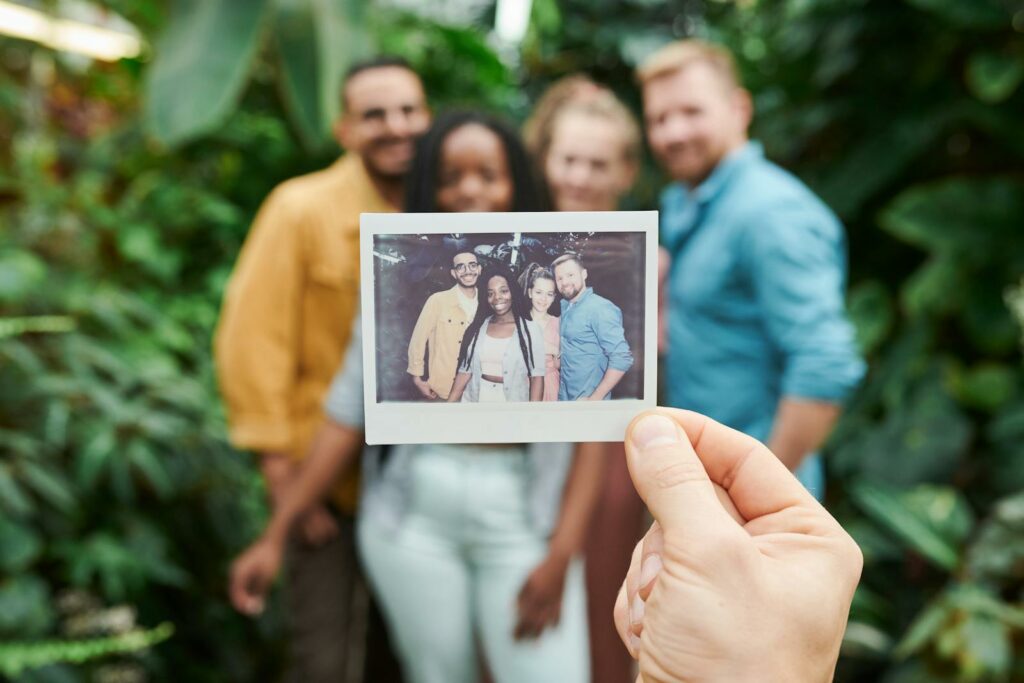 A group of friends enjoying a moment with an instant camera photo surrounded by lush greenery.